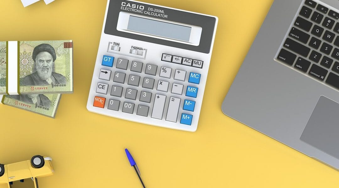 Calculator and laptop on a desk, illustrating whether AI can replace accountants